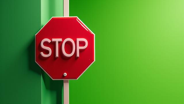 Signal stop rouge devant un champ vert, symbolisant le fait d'éviter le greenwashing.