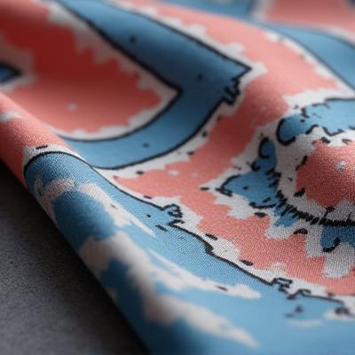 Foulard en soie aux motifs géométriques bleu et corail, maintenant épuisé.